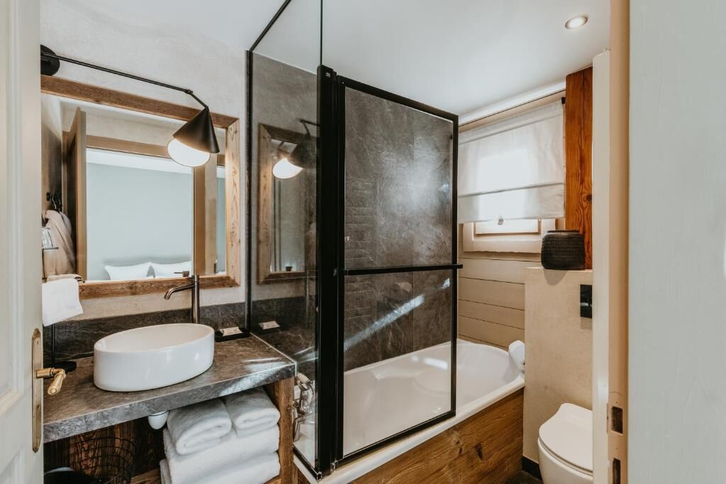 Un baño moderno con cabina de ducha de vidrio, un lavabo redondo y un inodoro.
