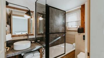 Un baño moderno con cabina de ducha de vidrio, un lavabo redondo y un inodoro.