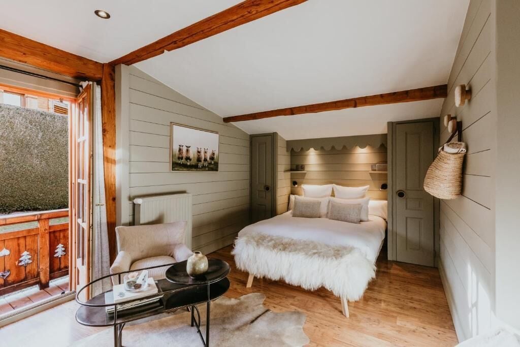 Quarto com cama, uma cadeira, uma mesa e uma janela com vista.