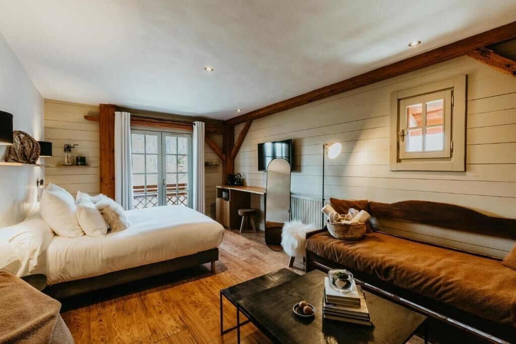 A cozy room with a bed, a sofa, a small table, and a window with curtains.