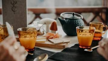 Una mesa con vasos de líquido ámbar, queso y una tetera, evocando un ambiente para comer.