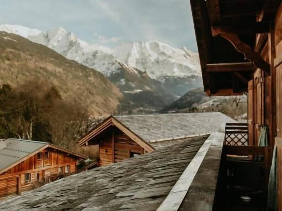 Una cabaña de madera con vistas a montañas nevadas y un glaciar.