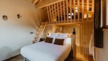 Een slaapkamer met een bed, nachtkastje, lamp, houten ladder en een raam.