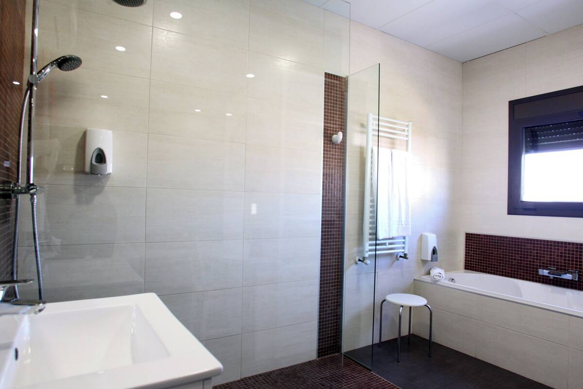 A modern bathroom with a glass-enclosed shower, a white sink, and a bathtub.