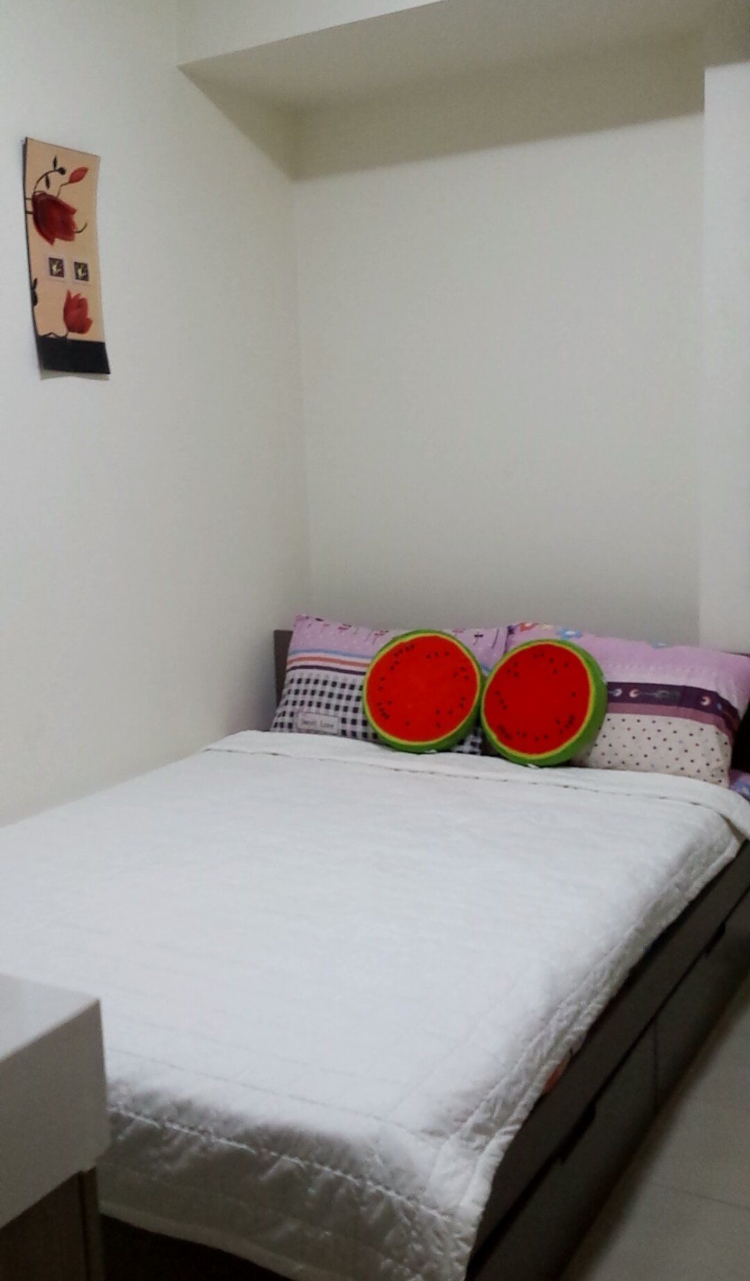A bedroom with a bed, pillows, and a wall decoration.