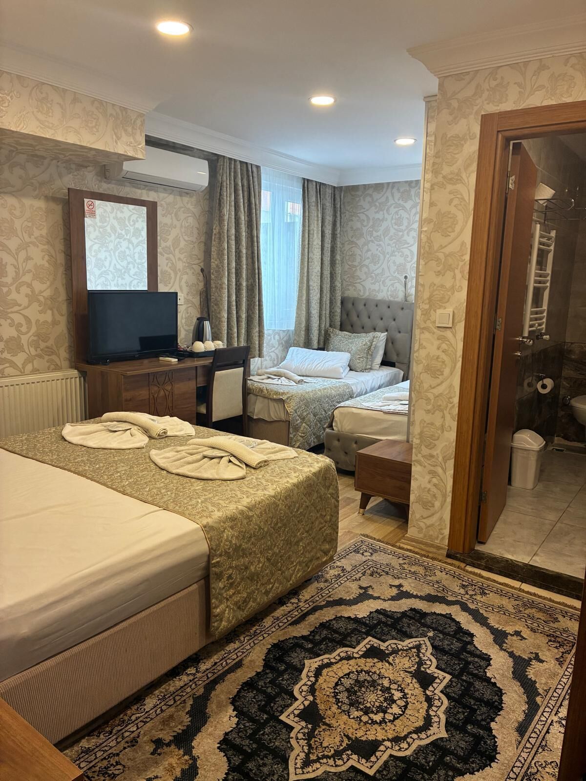Een hotelkamer met twee bedden, een bureau, een televisie en een badkamer.