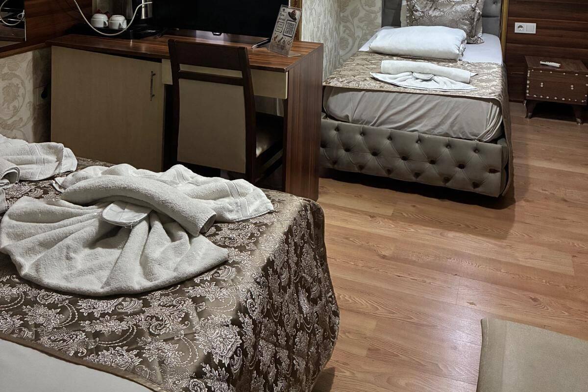 A hotel room with a bed, a desk with a television, a chair, and a wardrobe.