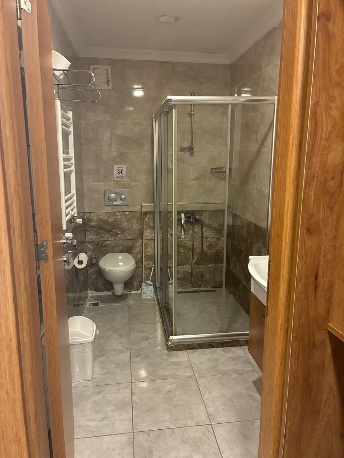 A modern bathroom with a glass-enclosed shower, a toilet, and a sink.