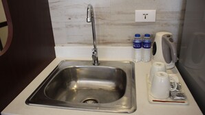 A stainless steel sink with a faucet, a coffee maker, and two bottles of water on the countertop. - Toyoko Inn Cebu (Mandaue)