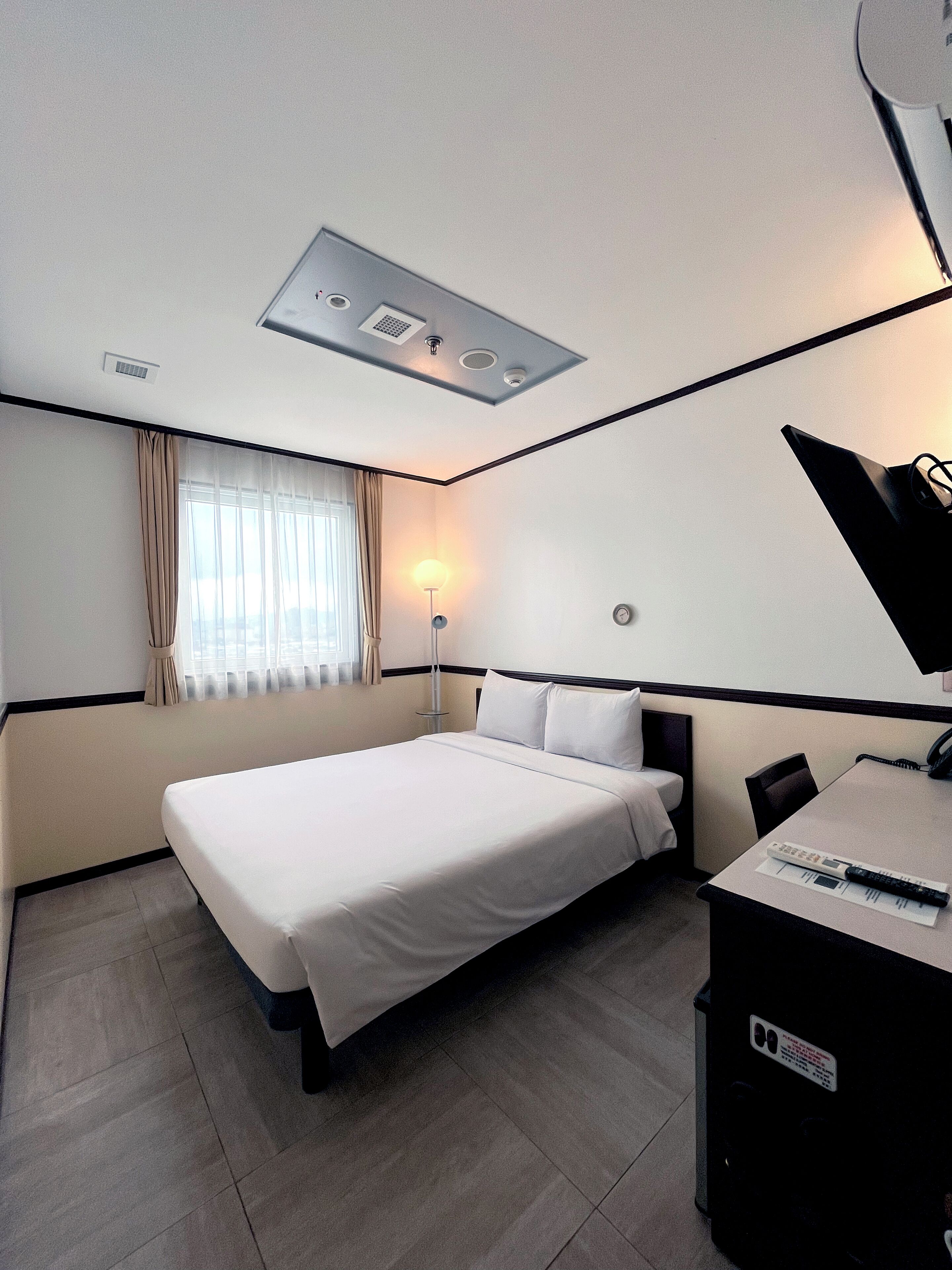 Una habitación de hotel con una cama, un escritorio, una lámpara y un teléfono.