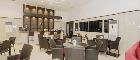 A hotel lobby with a bar area, seating arrangements, and a view through large windows.