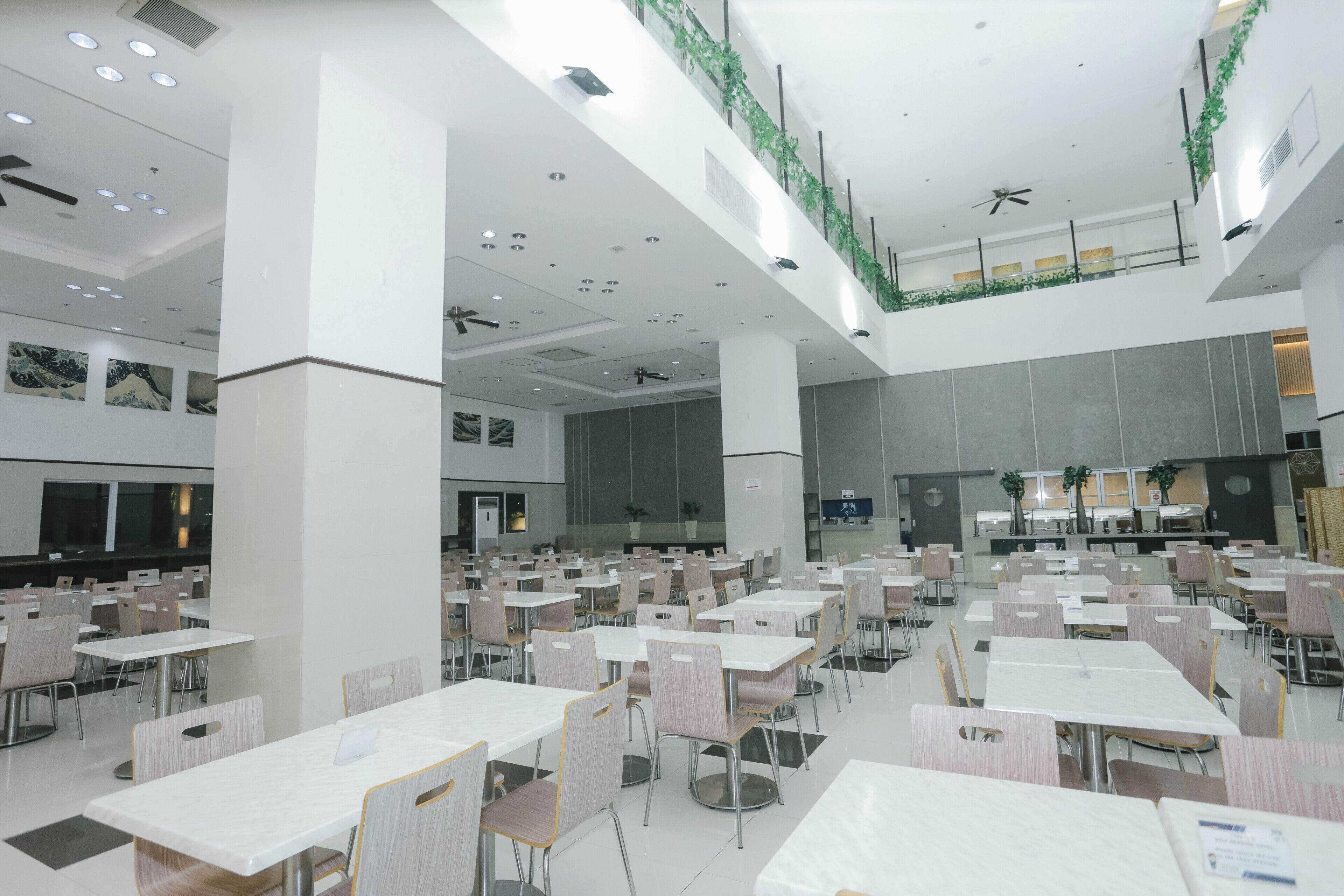 A spacious indoor dining area with multiple tables and chairs, ceiling fans, and recessed lighting.