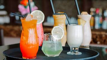 A tray with four different drinks, each with a straw and a slice of fruit.