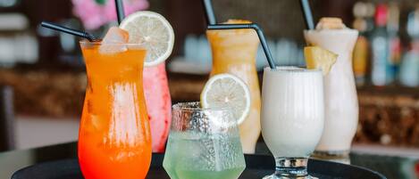 A tray with four different drinks, each with a straw and a slice of fruit.