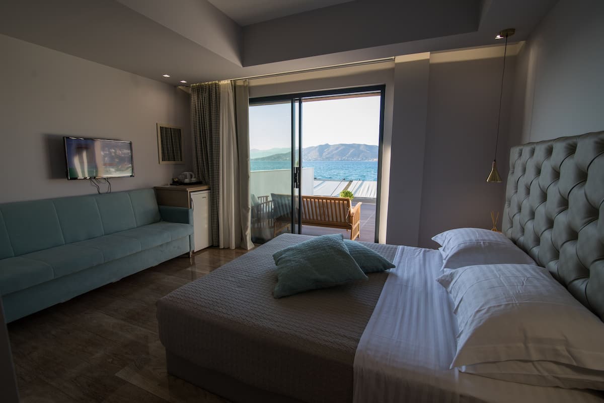 Un dormitorio con cama, sofá, televisión y vista al mar.