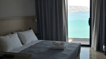 A hotel room with a bed, a desk, and a view of the sea.