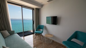 Une chambre moderne avec un canapé, deux fauteuils, un téléviseur et une vue sur la mer.