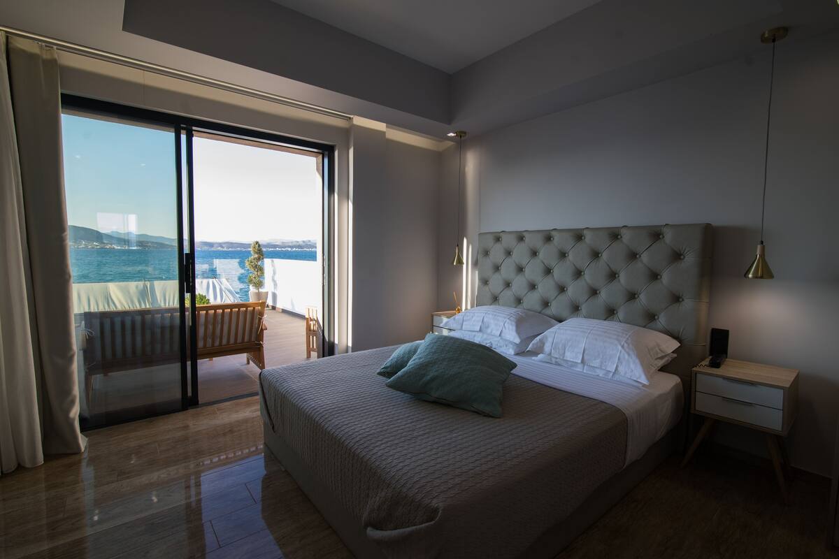 Un dormitorio con una cama grande, una mesita de noche y vista al mar a través de un ventanal corredero.