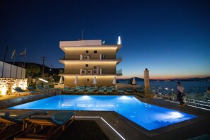 A multi-story building with a pool, lounge chairs, and umbrellas. - Aianteion Bay Luxury Hotel & Suites (Salamis)