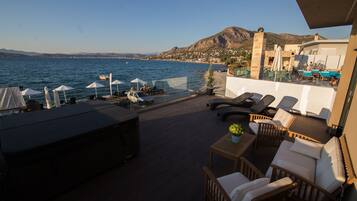 Una terraza con mobiliario exterior, piscina y vistas al mar y a las montañas.