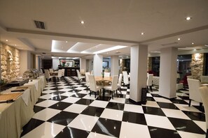 A spacious dining area with a checkered floor, multiple tables, and chairs. - Aianteion Bay Luxury Hotel & Suites (Salamis)