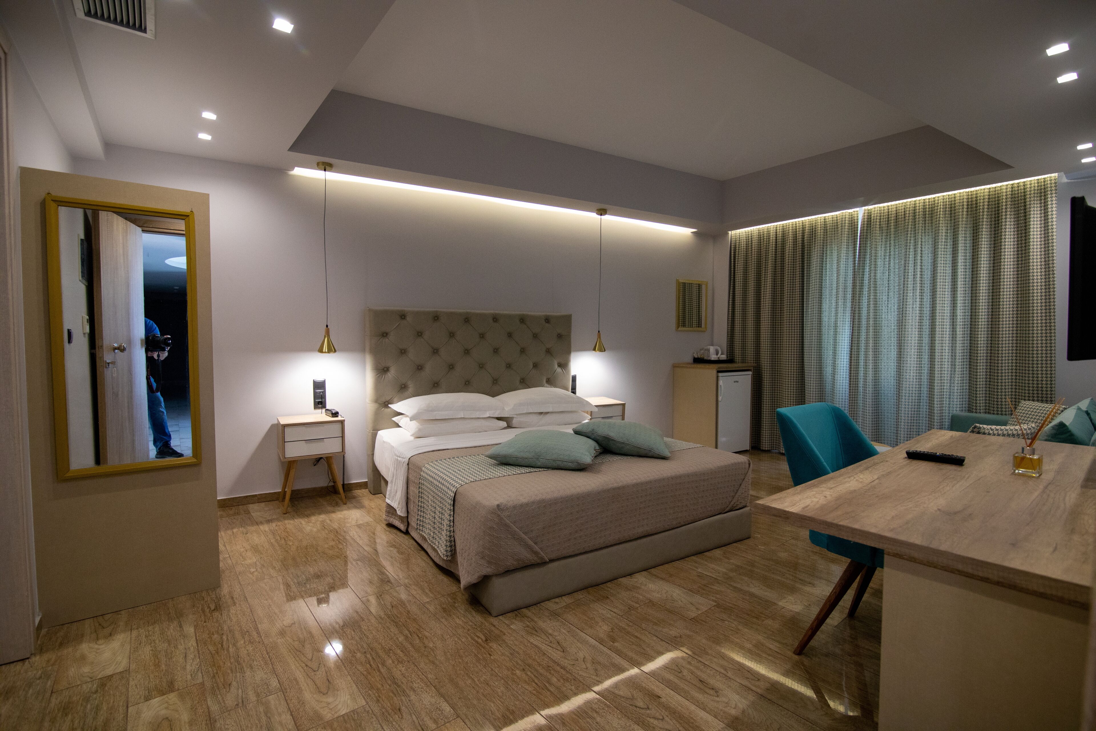 A modern bedroom with a bed, bedside tables, a desk, and a mirror.