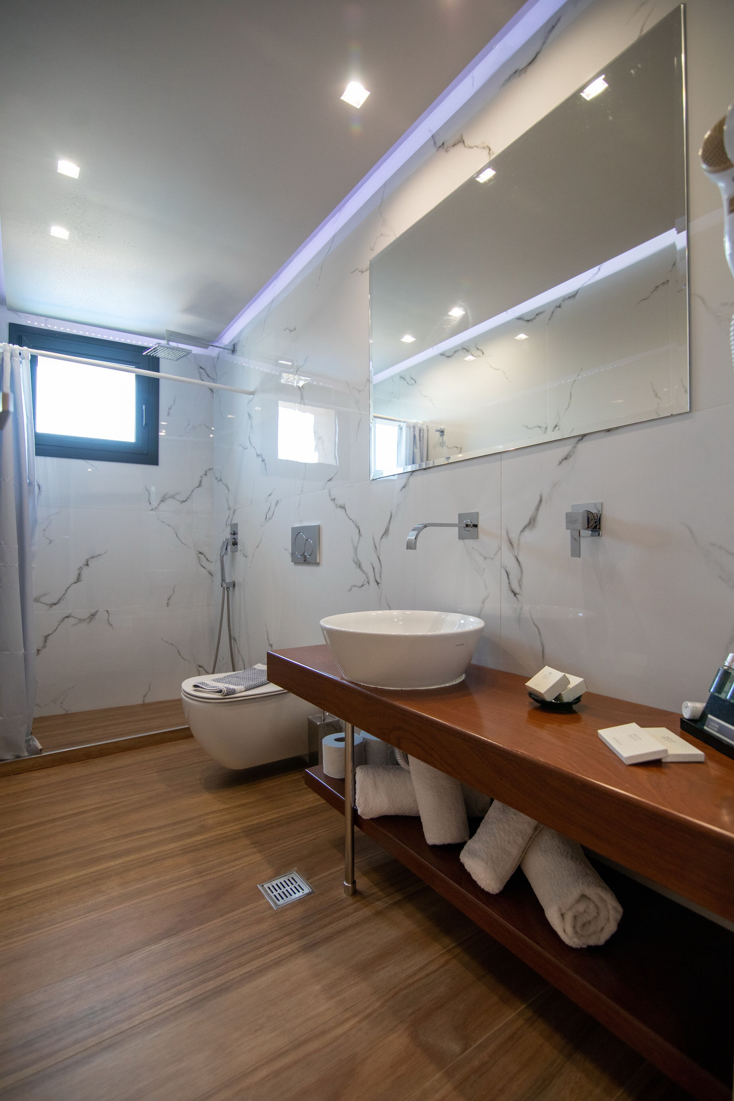 A modern bathroom with a large mirror, a white sink, and a shower.