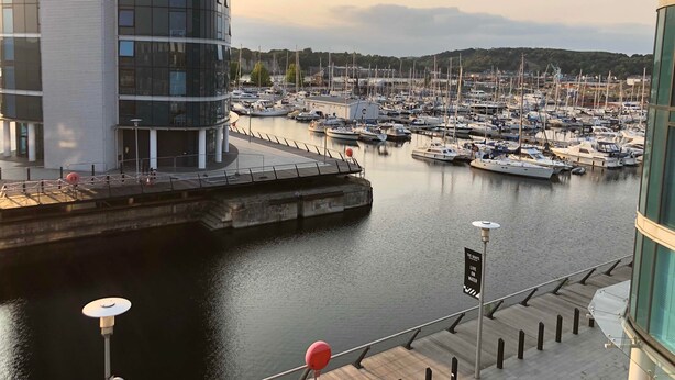 A marina with numerous boats docked, a modern building with large windows, and a sign that reads "THE BLAYS LIVE ON WATER." - The Wharf Medway (Chatham)
