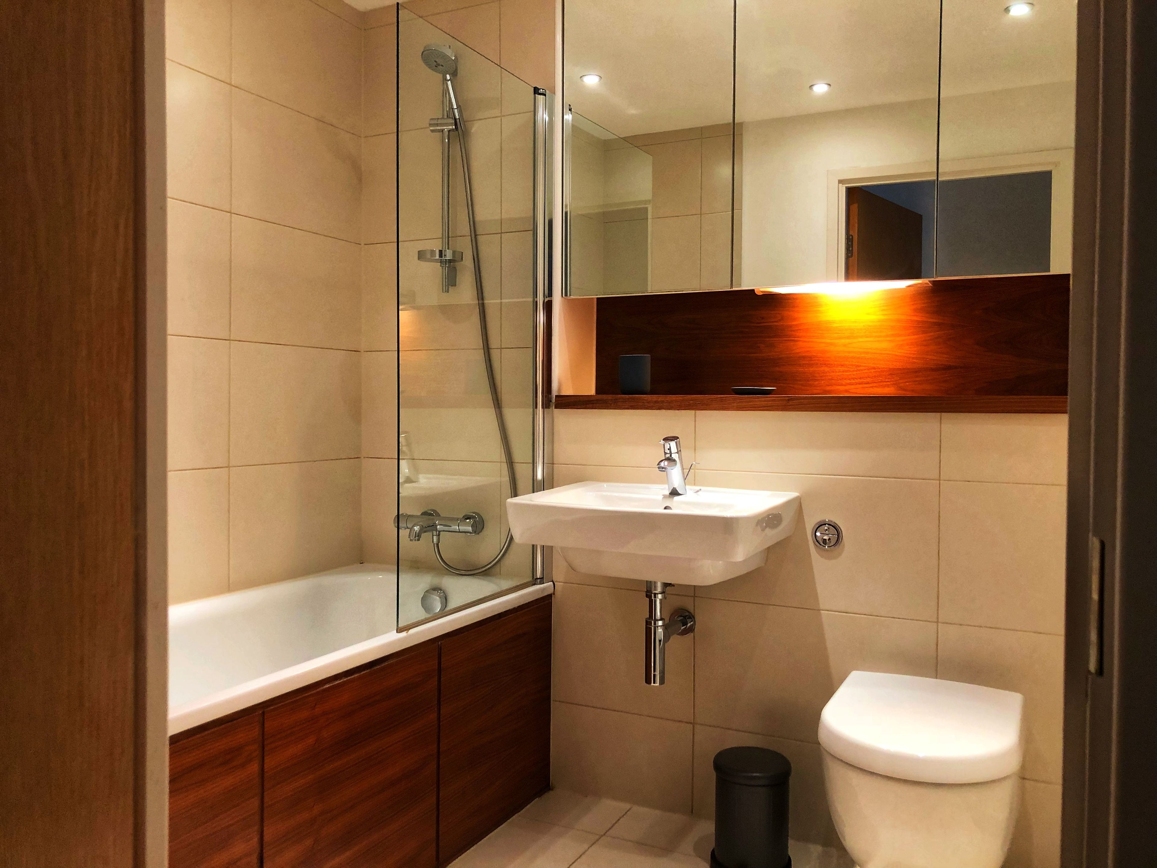 A modern bathroom with a glass-enclosed shower, a white sink, and a toilet.