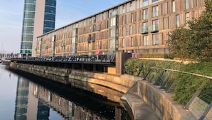 A modern building with a glass facade and wooden paneling, adjacent to a body of water. - The Wharf Medway (Chatham)