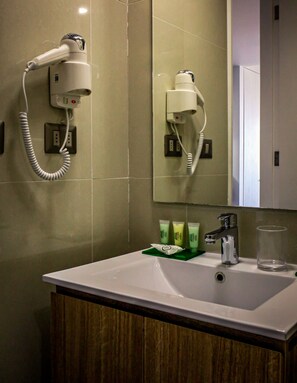 A bathroom with a white sink, a mirror, a hairdryer, and a glass. - EcoApart Antofagasta (Antofagasta)