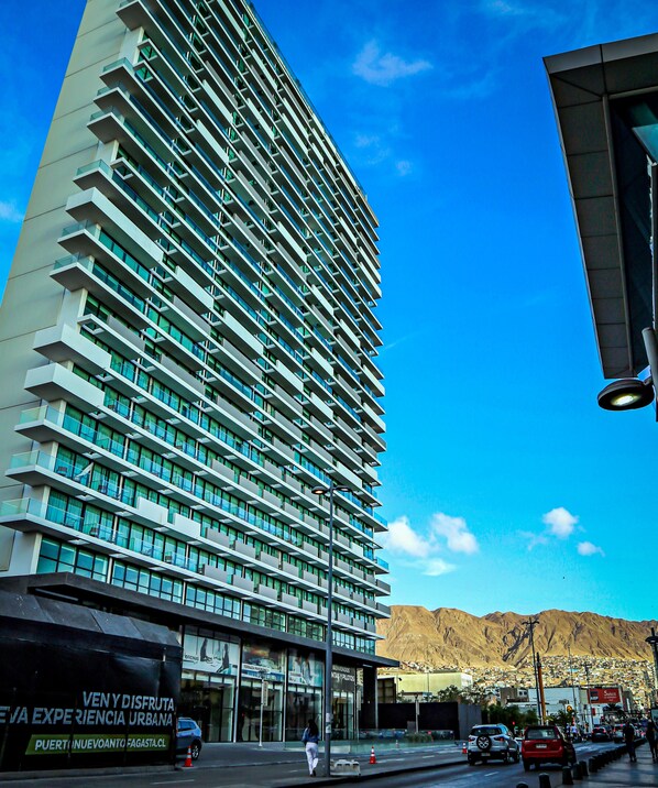 A tall, modern hotel with a prominent glass facade and multiple balconies. - EcoApart Antofagasta (Antofagasta)