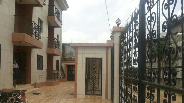 Zona residencial cerrada con un patio empedrado, una motocicleta estacionada y un edificio con balcones.