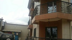 Un edificio residencial de varios pisos con un balcón, un coche aparcado y una puerta de garaje visible.
