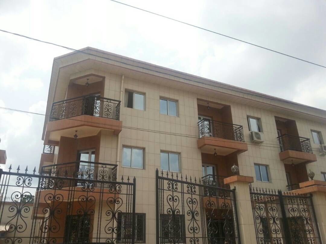 A multi-story residential building with balconies, a gated entrance, and a tiled facade.