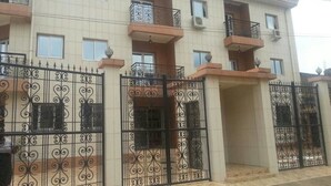 Un edificio residencial de varios pisos con balcones y una entrada protegida por una verja.