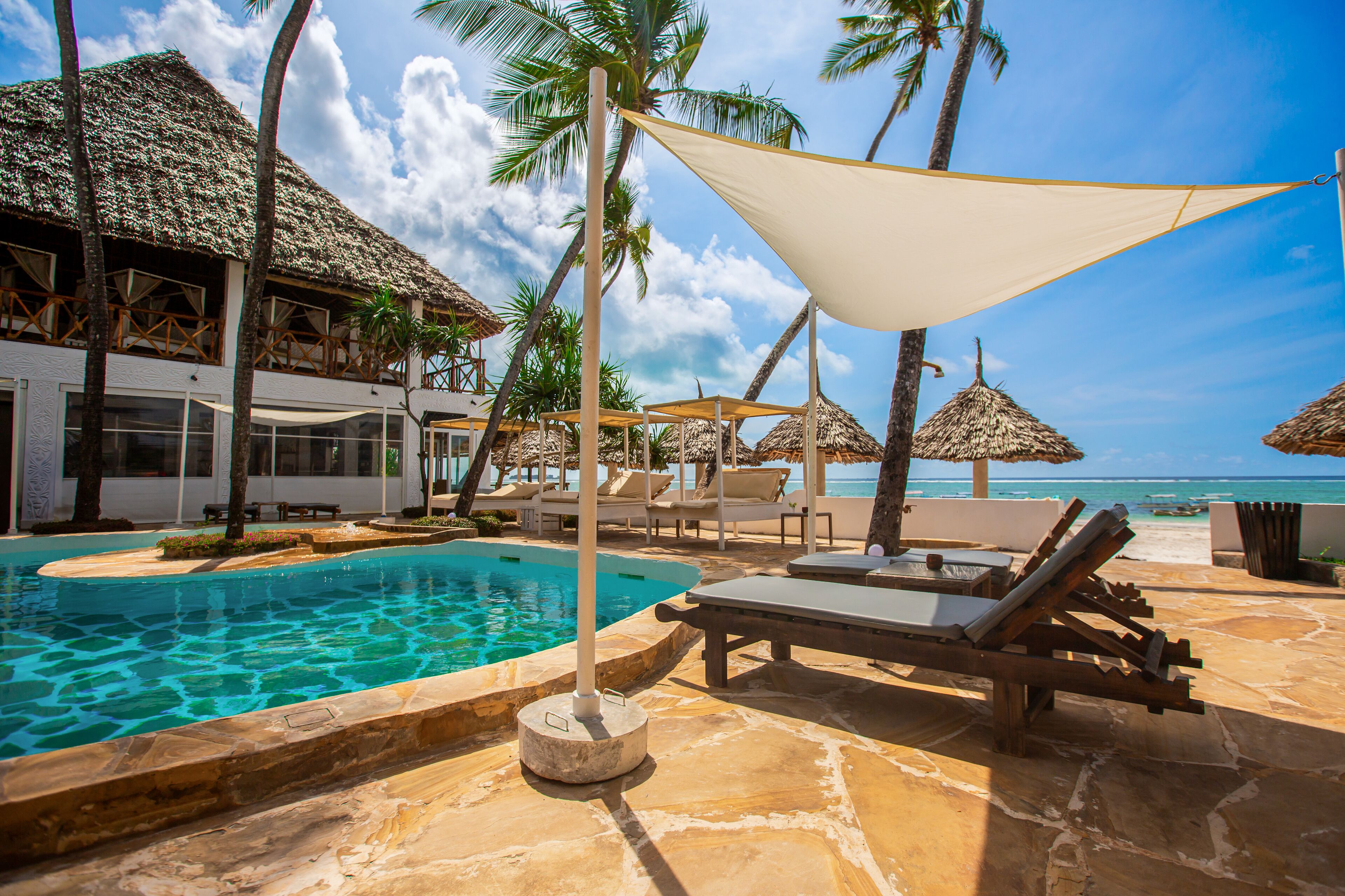 A resort pool area with lounge chairs, umbrellas, and a view of the ocean.