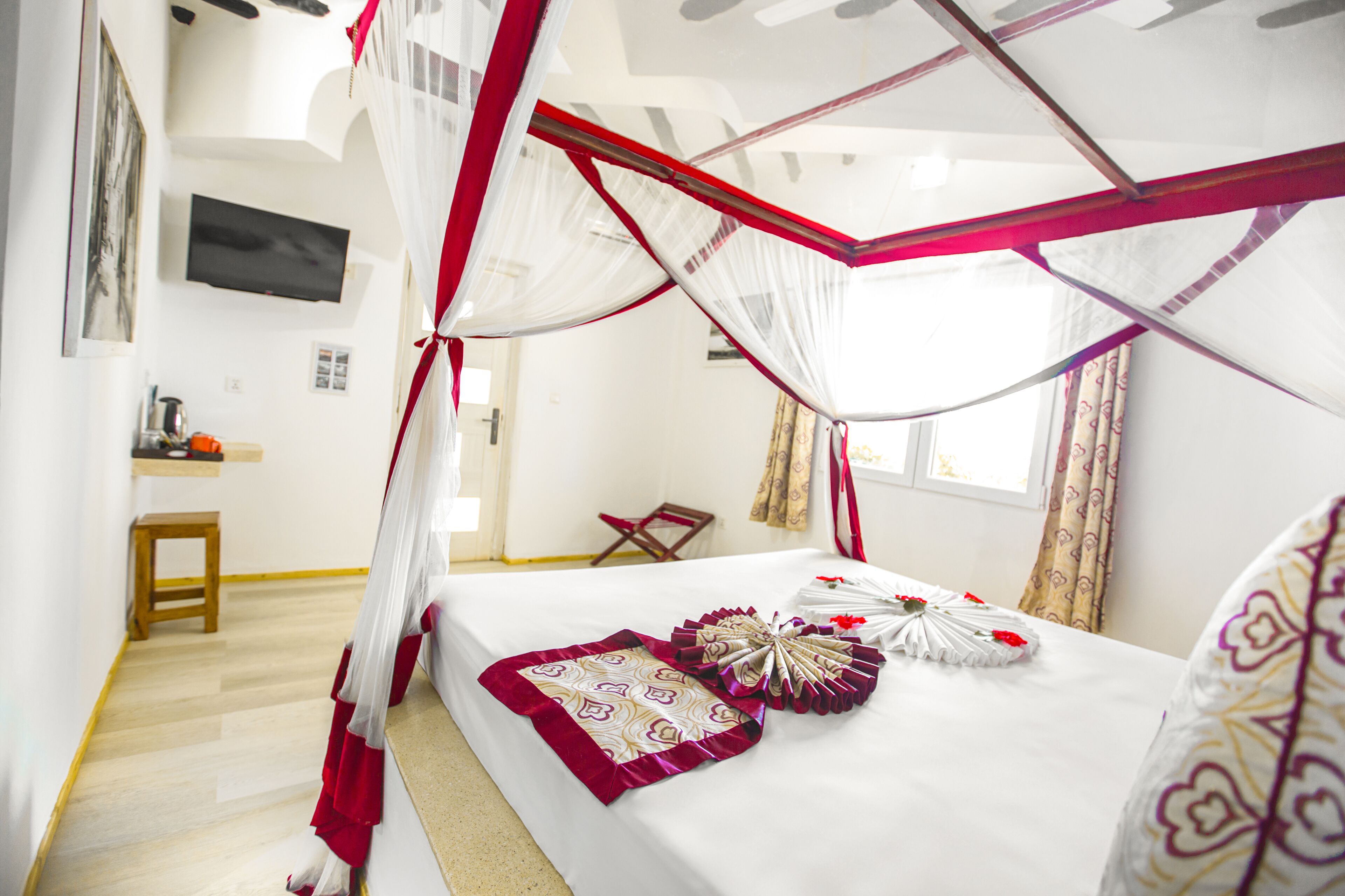 Una camera da letto con un letto a baldacchino, un comodino, una sedia e una televisione appesa al muro.