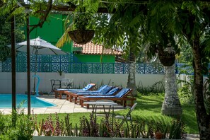 Relax by the serene pool surrounded by a lush garden and comfortable lounge seating.