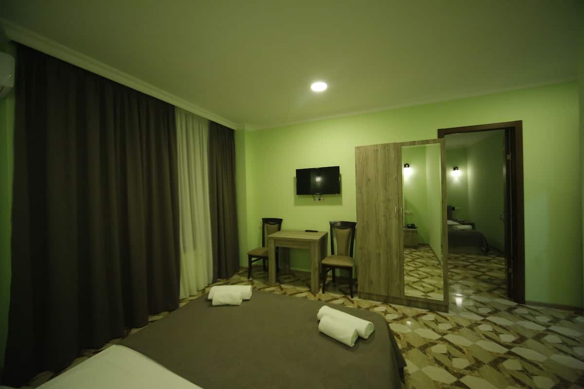 Ein Hotelzimmer mit Bett, Schreibtisch, Stuhl, Fernseher und Spiegel.
