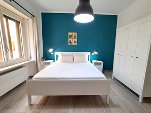 Un dormitorio con cama, mesitas de noche, armario y ventana.