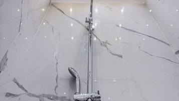 A modern bathroom with a shower, chrome fixtures, and marble flooring.