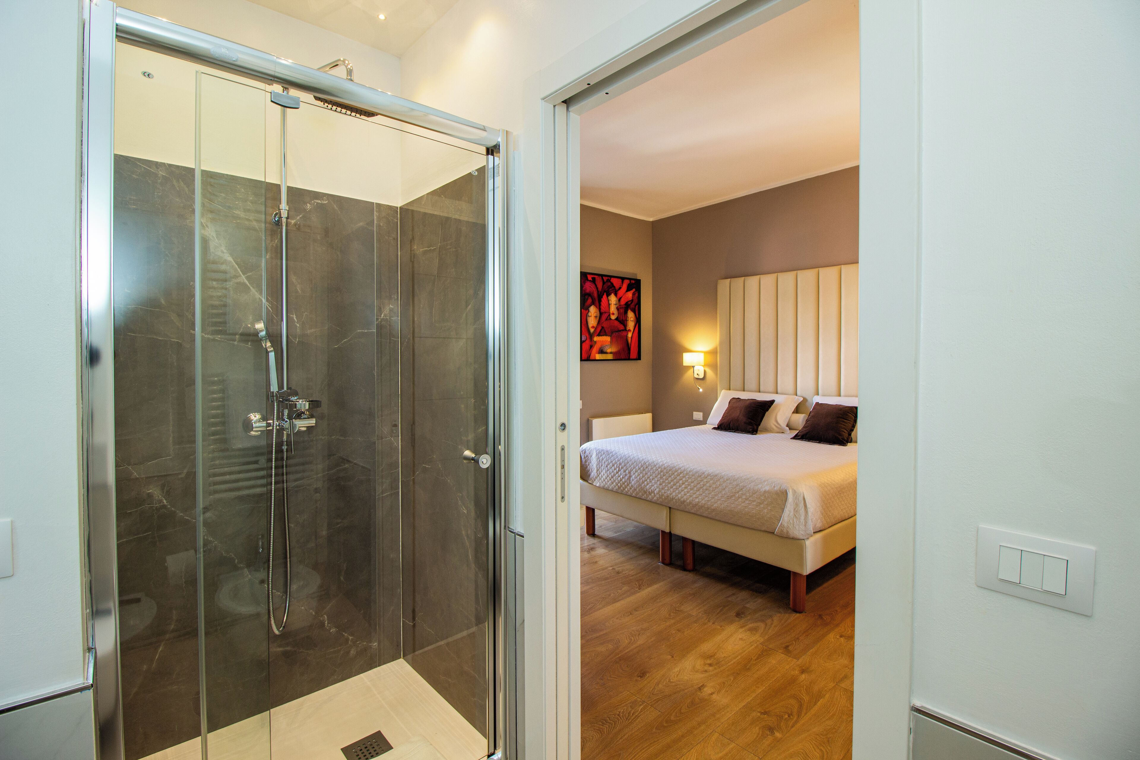 A modern bathroom with a glass-enclosed shower and a wooden floor.
