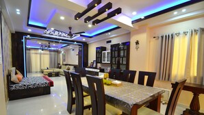 A modern dining area with a long table, chairs, and a ceiling fan. - Tulip Residency (Dibrugarh)