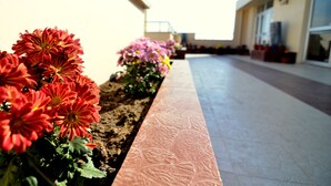 A flower bed with red and pink flowers along a building's exterior wall. - Tulip Residency (Dibrugarh)