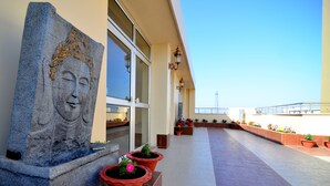 A building exterior with a Buddha statue, potted plants, and a clear sky. - Tulip Residency (Dibrugarh)