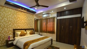 A bedroom with a bed, nightstand, wardrobe, and ceiling fan. - Tulip Residency (Dibrugarh)