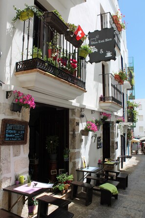 Un café avec une terrasse, une enseigne sur laquelle on peut lire « Dios Está Bien », et des plantes en pot sur le balcon.