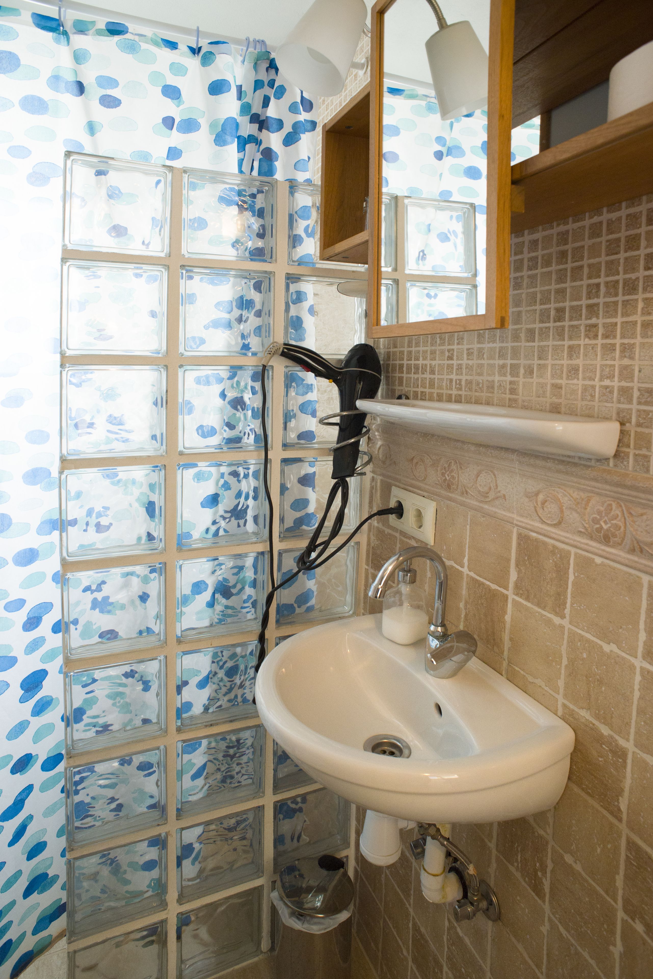 Une salle de bain avec une douche à parois en verre, un lavabo blanc et un miroir au-dessus.