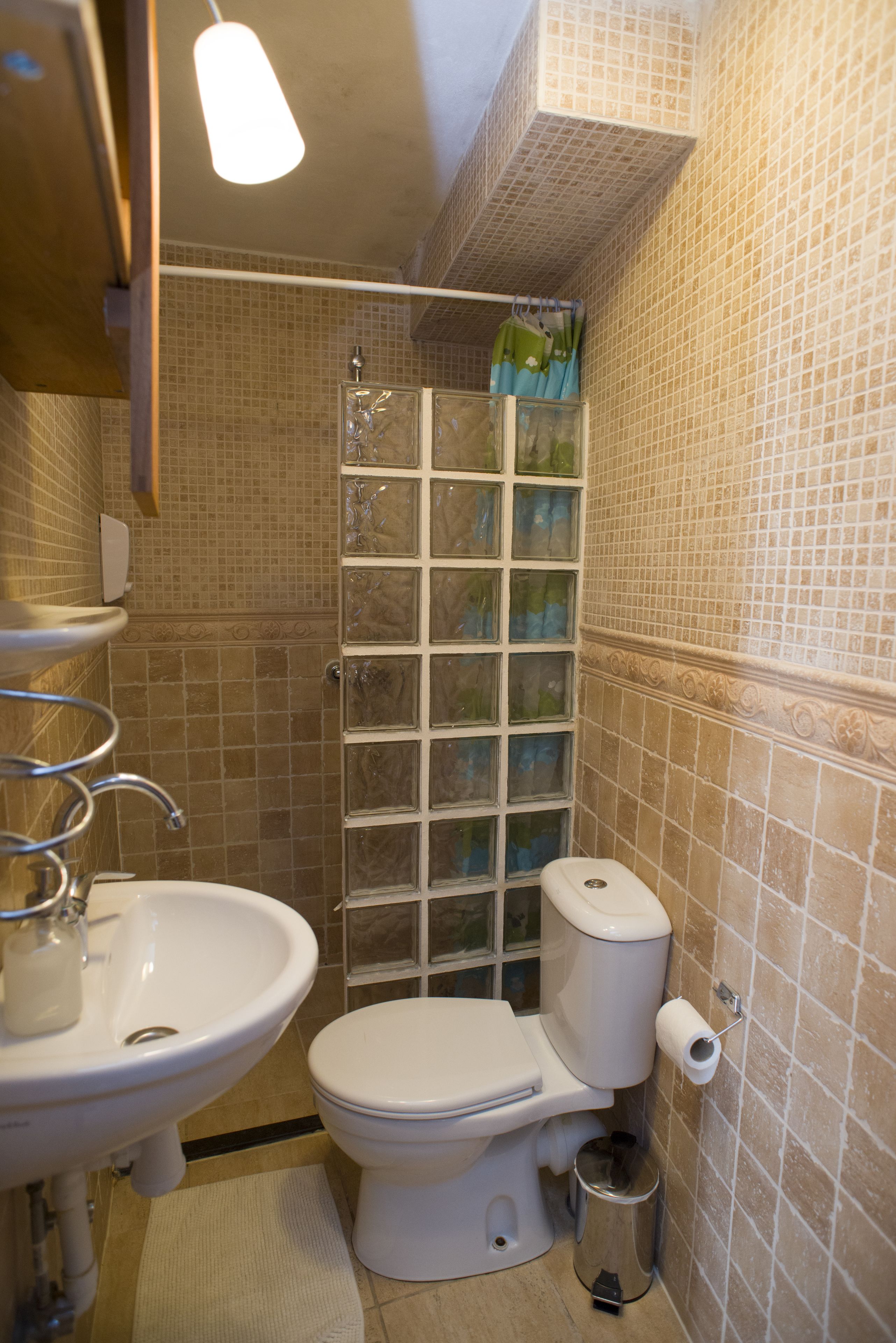 A bathroom with a sink, toilet, and shower enclosure.